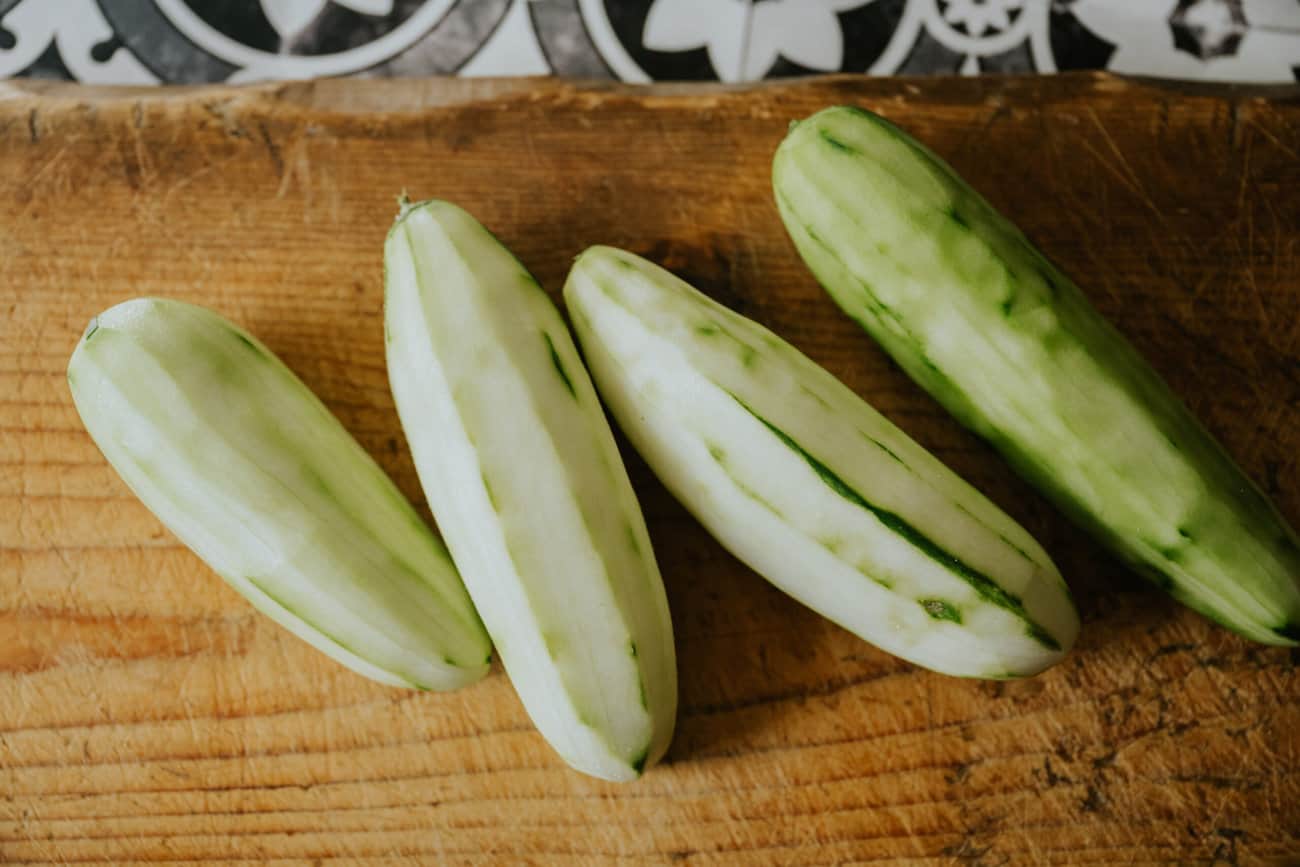 4 whole peeled cucumbers on a cutting board. 