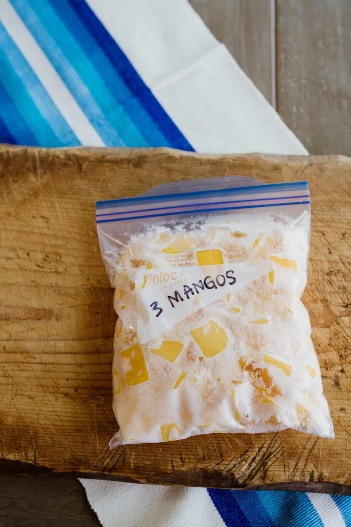zip-top freezer bag filled with 3 frozen mangoes that have been cut into cubes. 