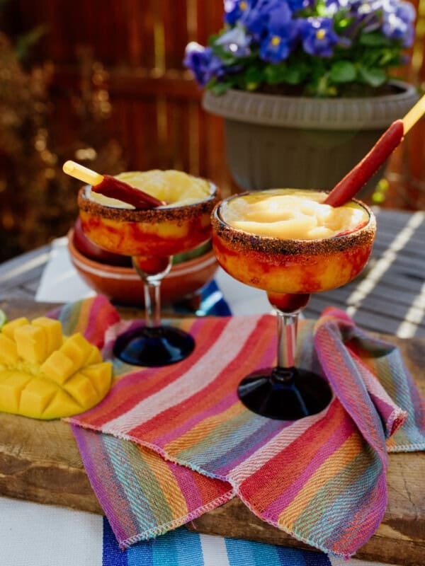 two margarita glasses filled with frozen mangonada margarita and garnished with tarugos straws.