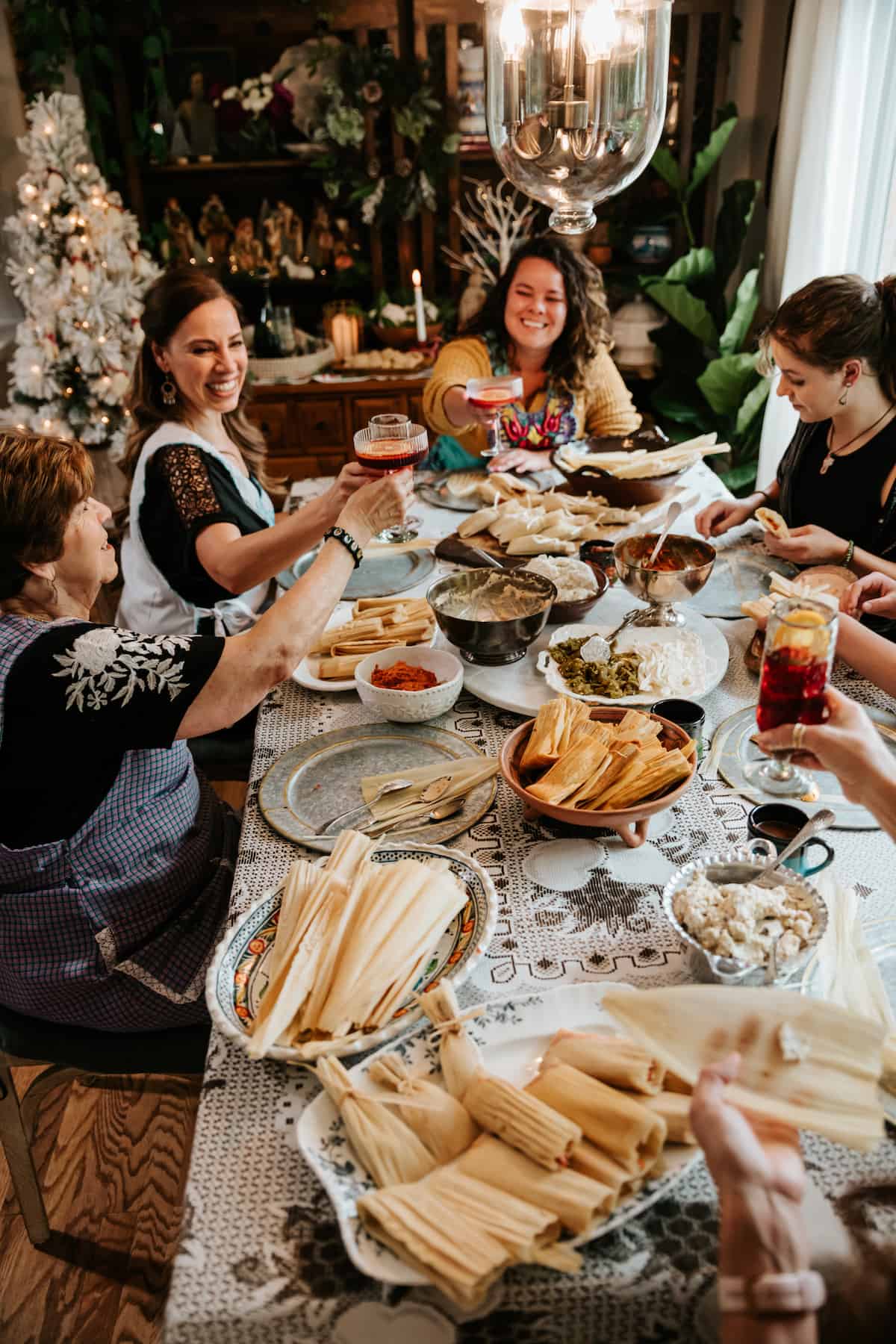 women gathered around a festive table assembling tamales at a tamalada. 