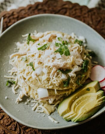 stack of green enchiladas verdes layered with shredded chicken, cheese, and creamy roasted green chile sauce.