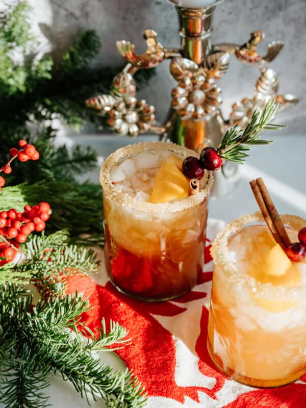 spiced pomegranate cranberry holiday margarita garnished with rosemary, cranberries, and orange peel.