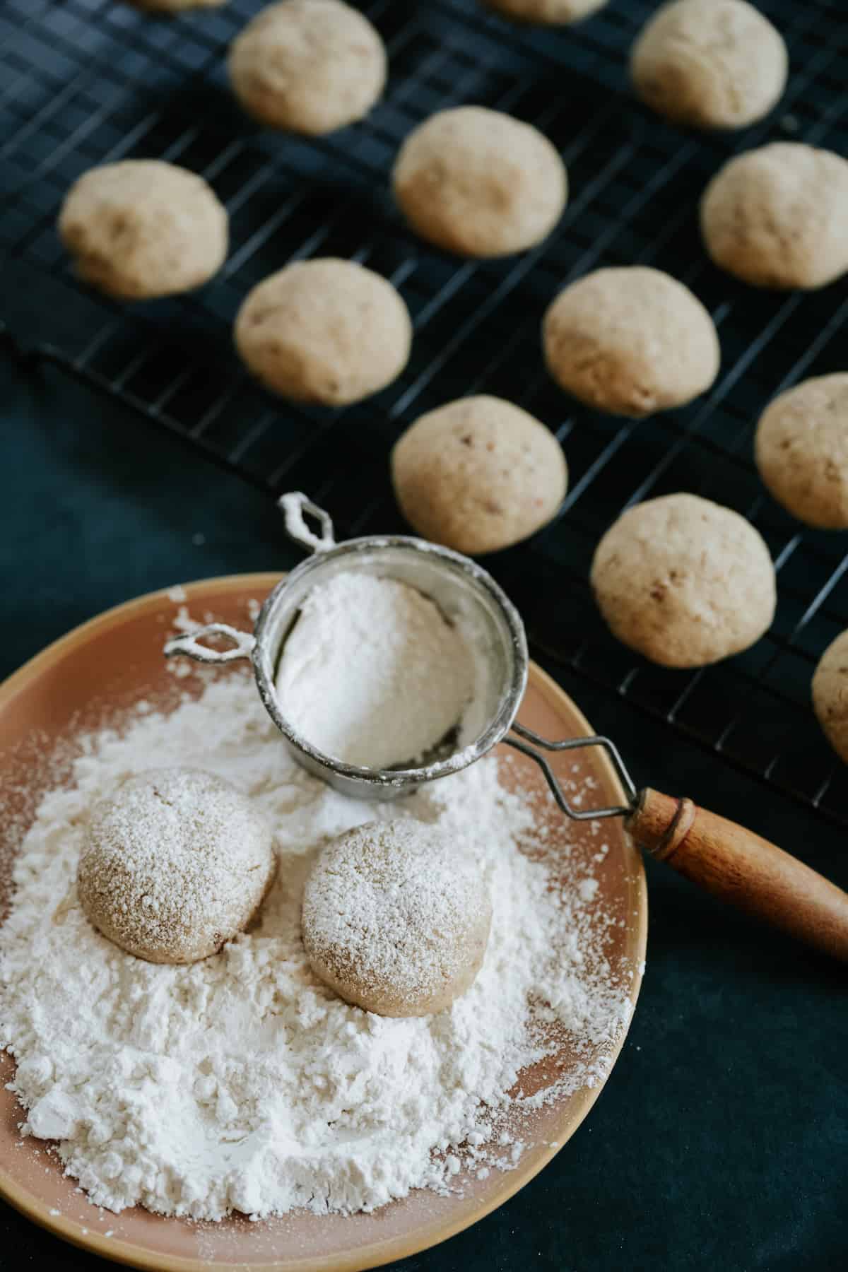 Polvorones Cookies (Mexican Wedding Cookies) that are being dusted with powdered sugar.