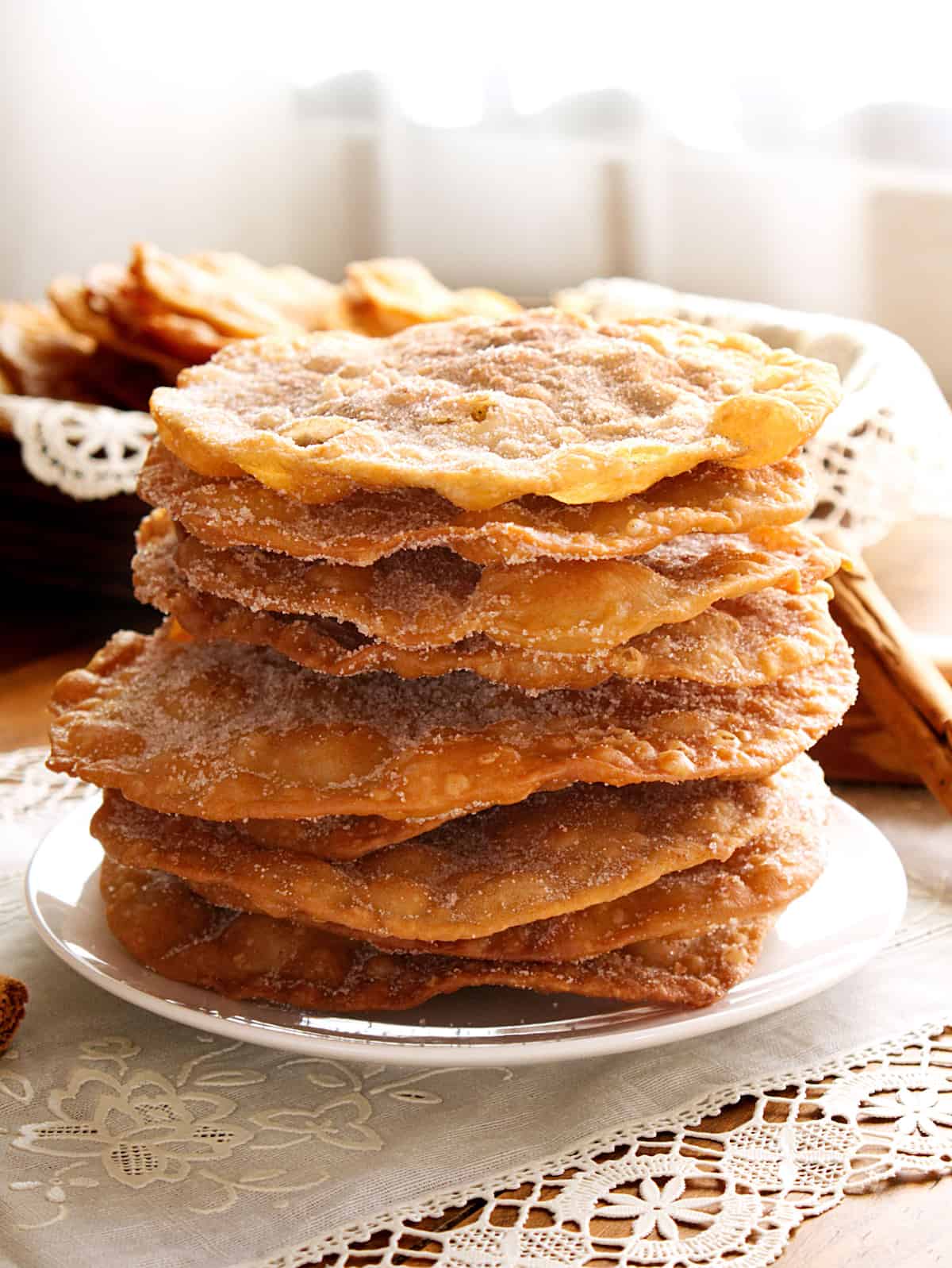 side on shot of a tall stack of cinnamon sugar dusted buñuelos mexicanos.