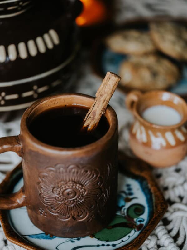 hand carved barro holding cafe de olla with a cinnamon stick stir stick.