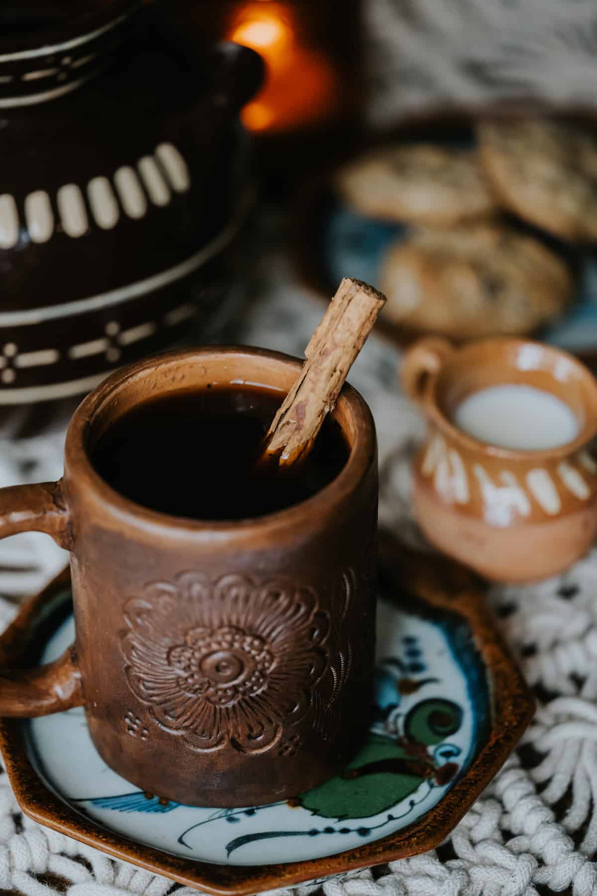 hand carved barro holding cafe de olla with a cinnamon stick stir stick. 
