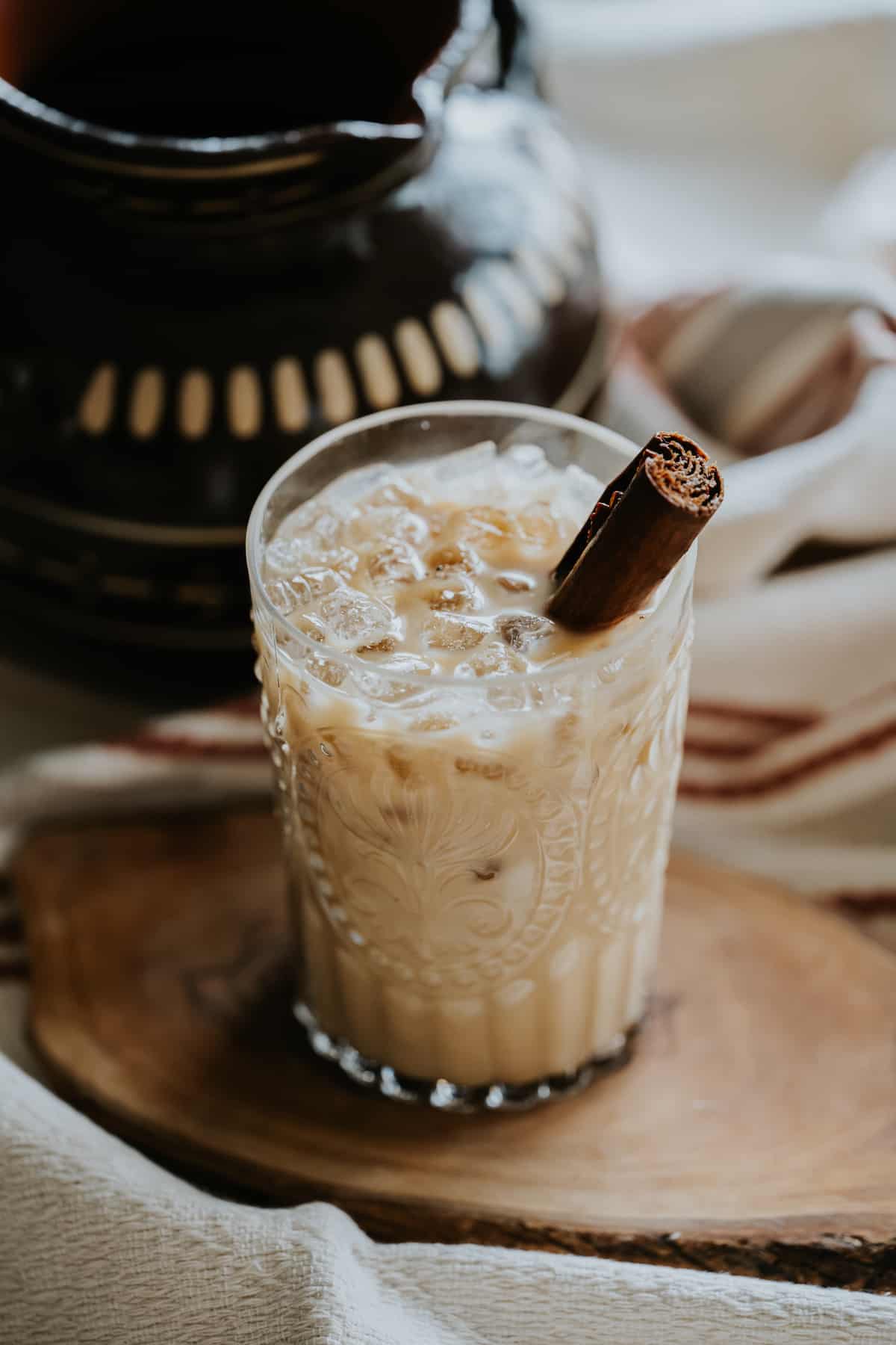 iced cafe de olla con leche in a decorative clear glass on a wood slice. 