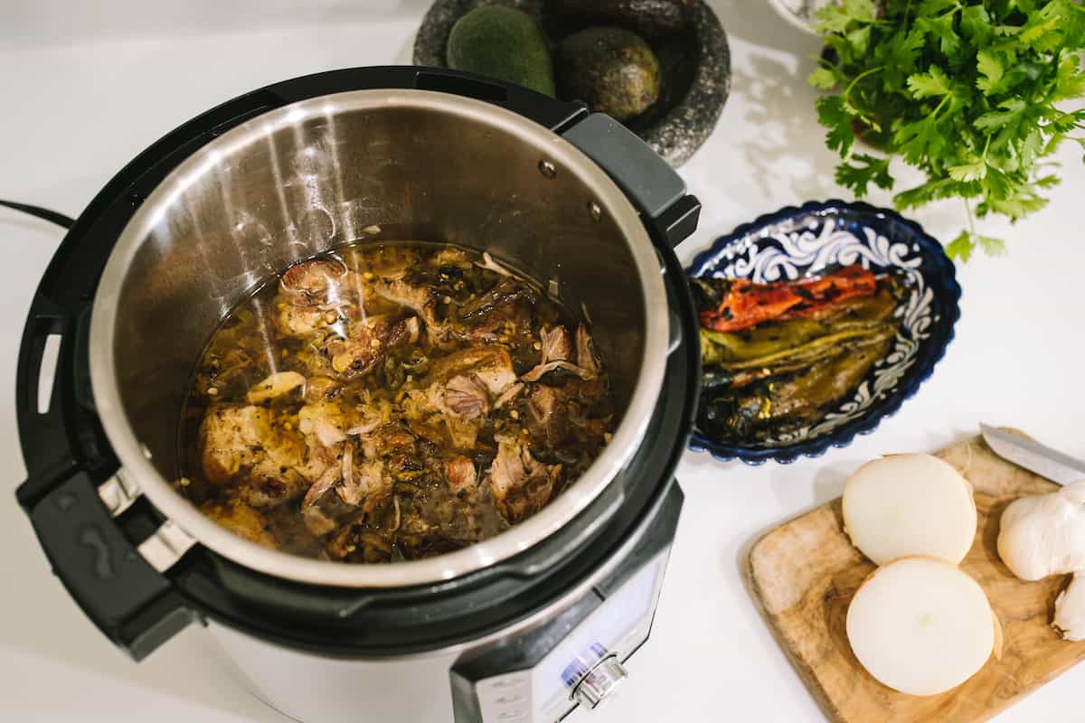 Pork and Roasted Green Chile filling for Tamales in an instant pot on a white table.
