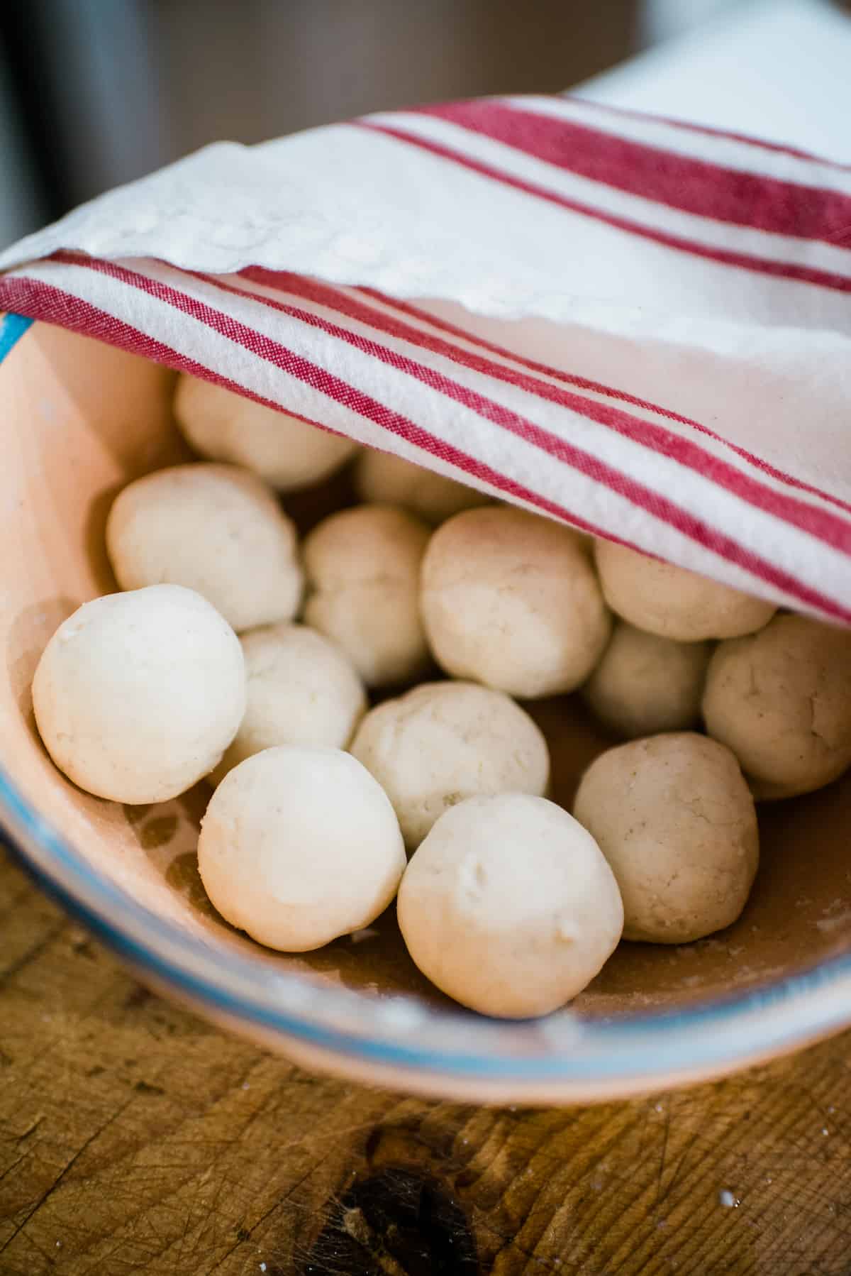 closeup shot of a towel-covered bowl with about a dozen balls of masa dough that are ready to be turned into sopes. 