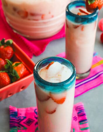 hero shot of a tall collins glass filled with strawberry horchata, strawberry slices, and ice.
