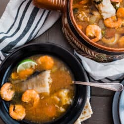 table with bowls of caldo de camaron y pescado with a serving bowl of more Mexican fish soup.