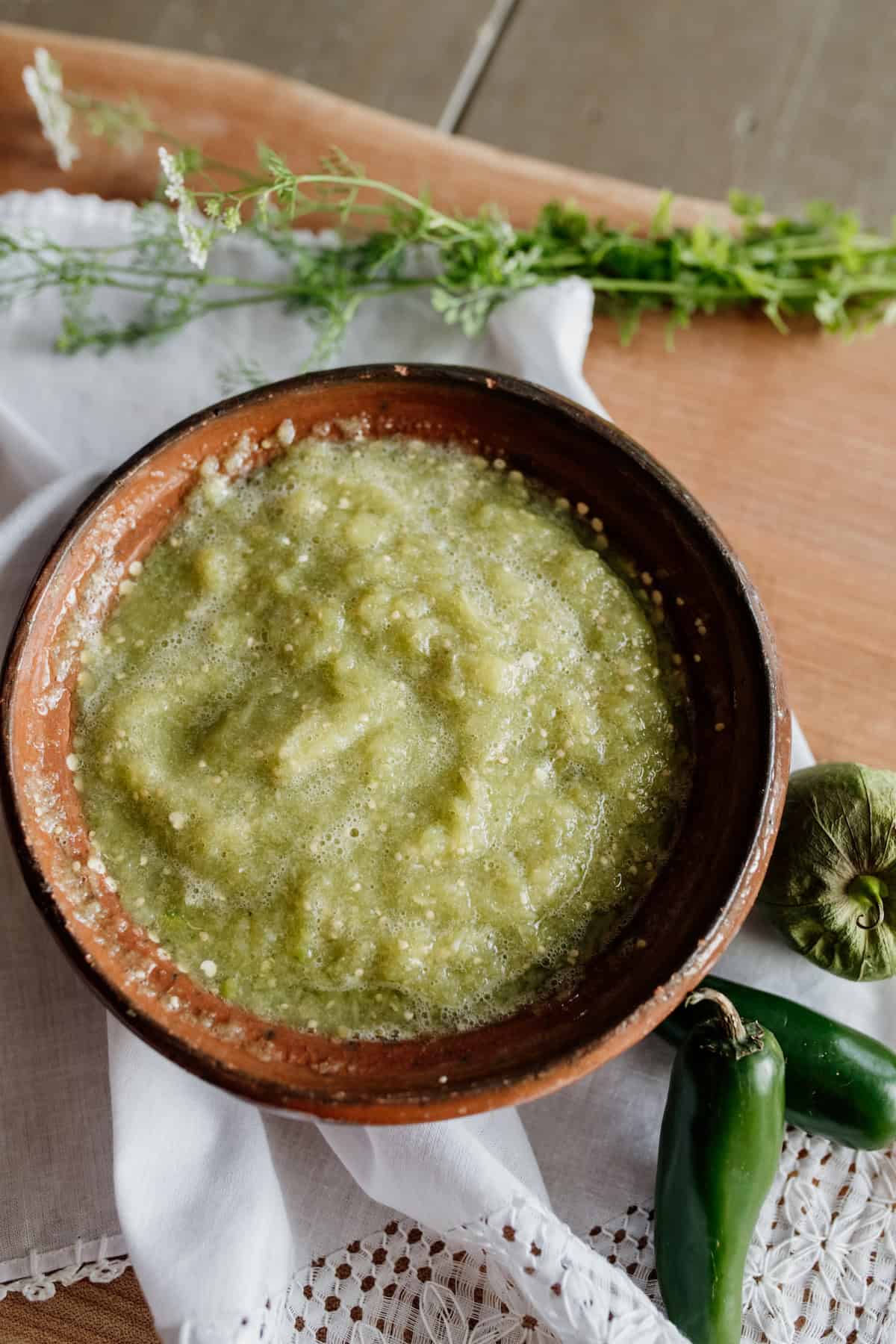 Barro brown Mexican pottery bowl filled with homemade Mexican salsa verde with jalapeño tomatillo and cilantro on the side.