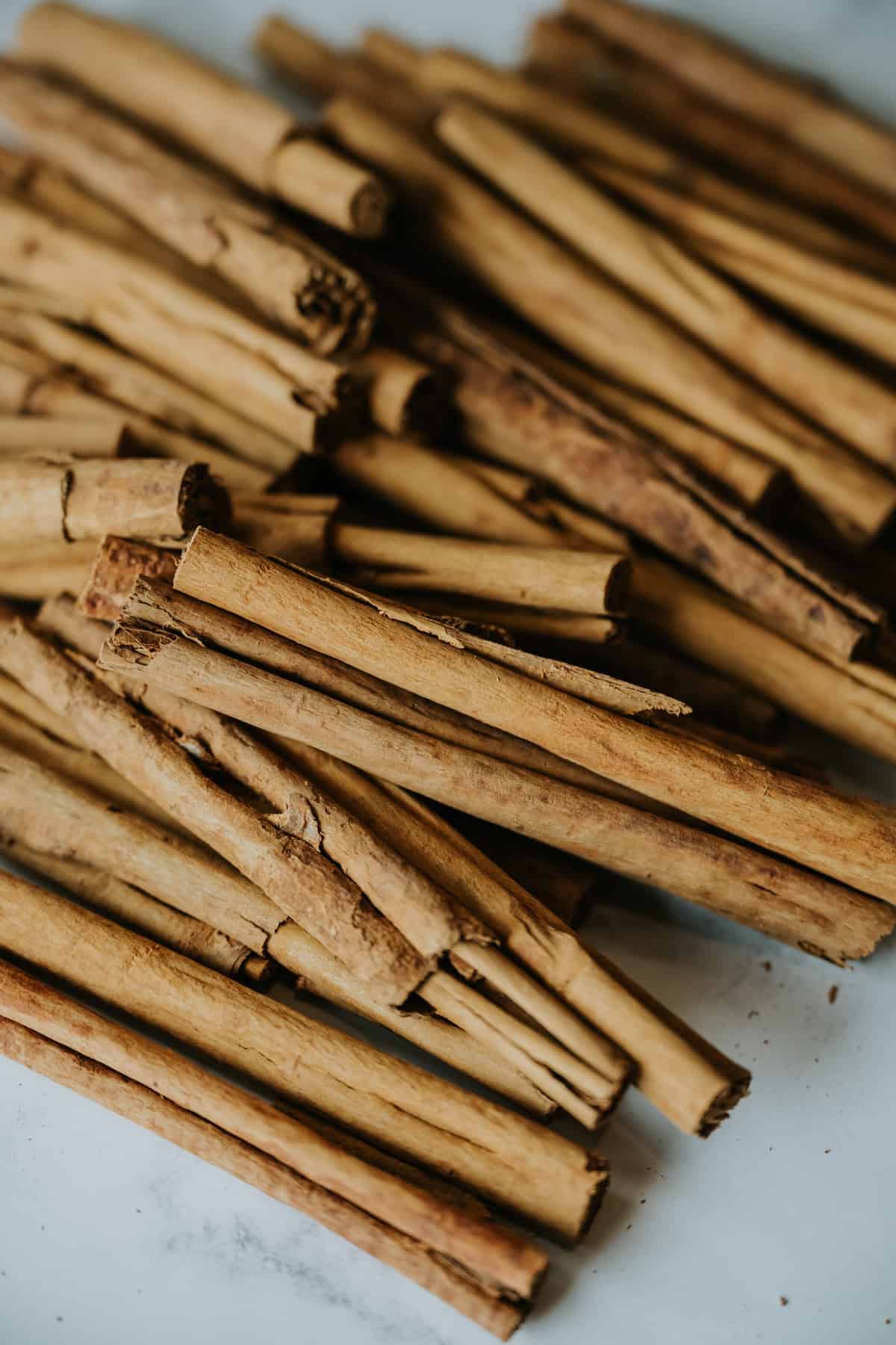 a pile of Mexican cinnamon sticks (also known as canela) on a white table.