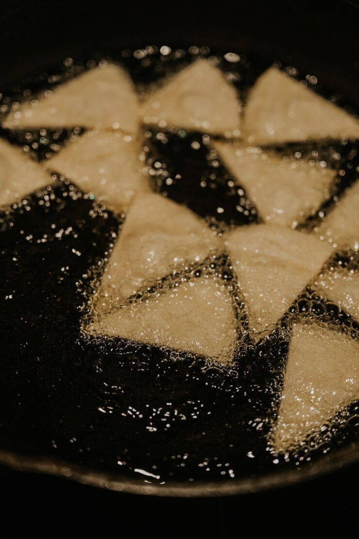 Corn tortilla wedges frying until crisp and golden for authentic Chilaquiles Rojos.
