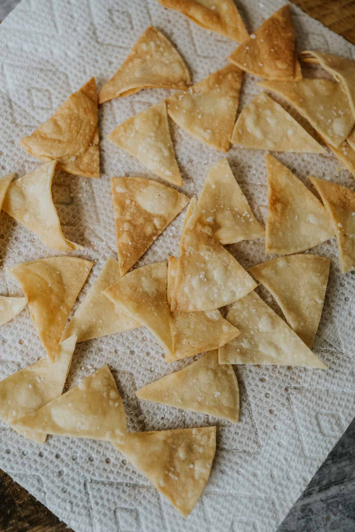 salted and fried tortilla chips draining on paper towels. 