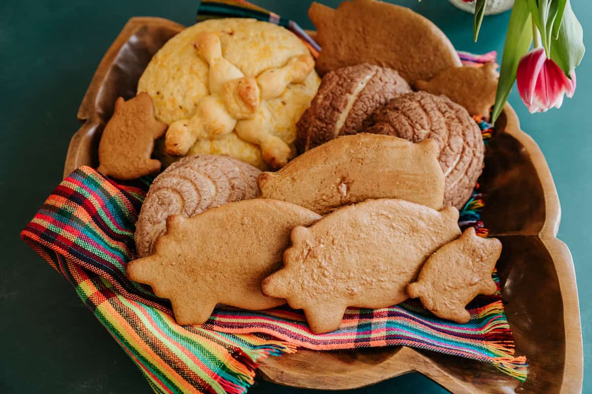 basket of pan dulce with large and small marranito cookies in the front, conchas behind. 