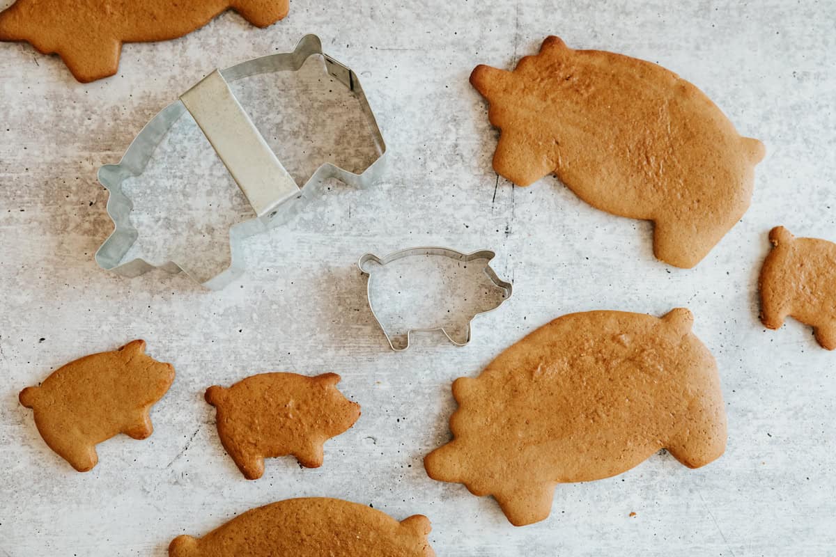 baked marranitos pan dulce with two sizes of pig cookie cutters on a grey slate surface. 