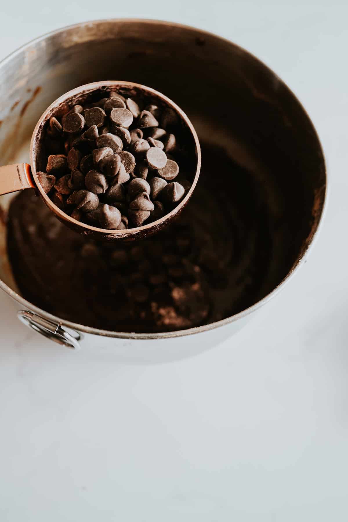 Adding chocolate chips into brownie batter. 