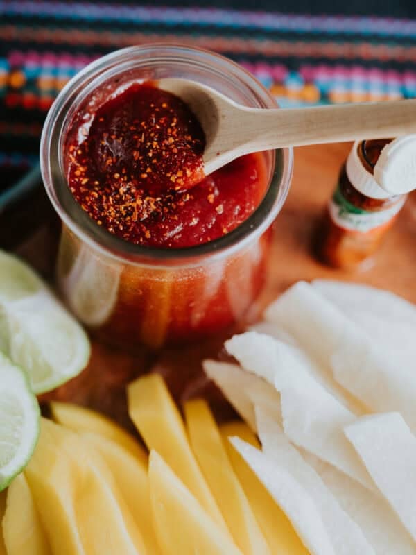 homemade chamoy sauce in a glass jar with a wooden spoon.