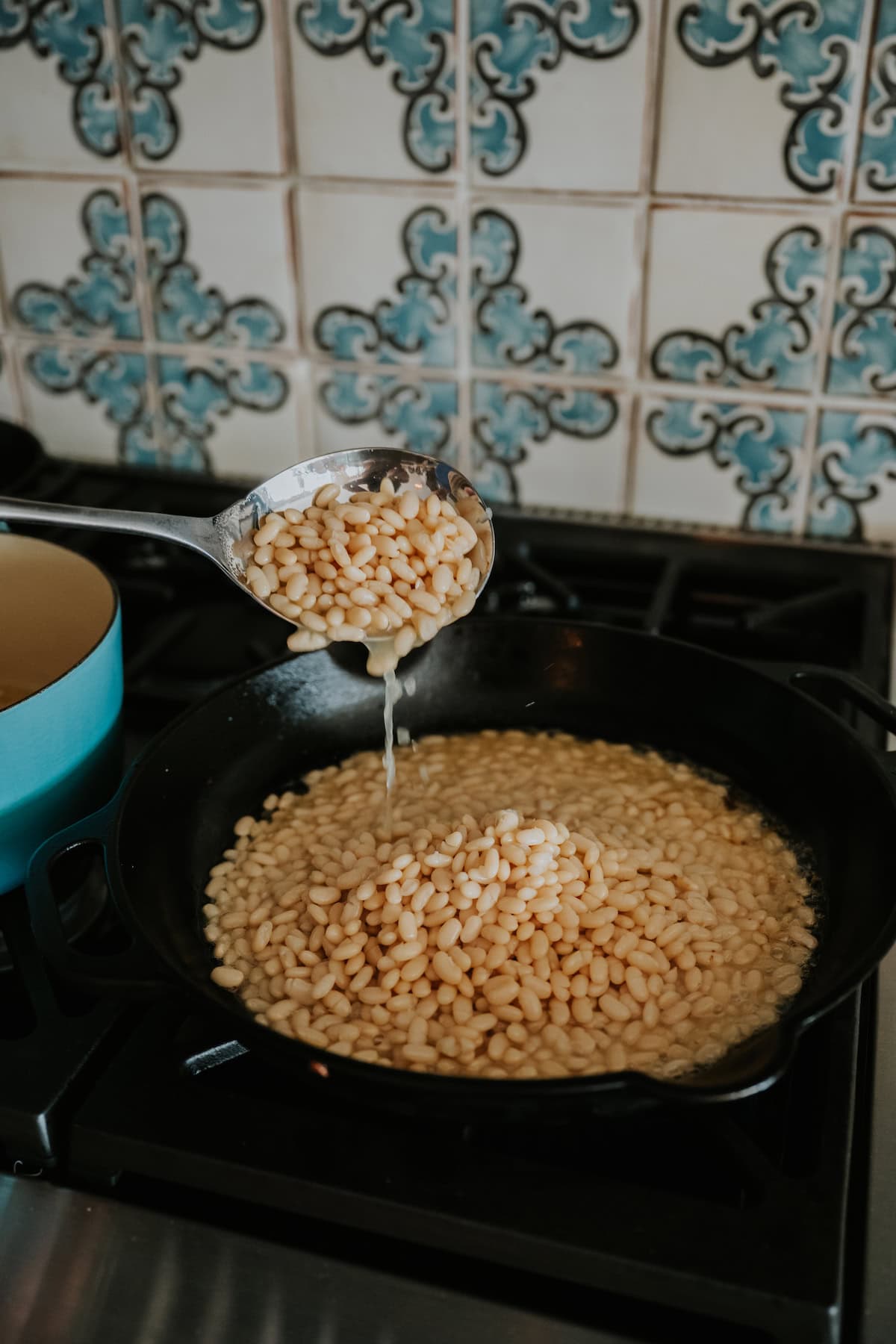 cooked beans and potlikker being spooned into a skillet with the bacon fat. 