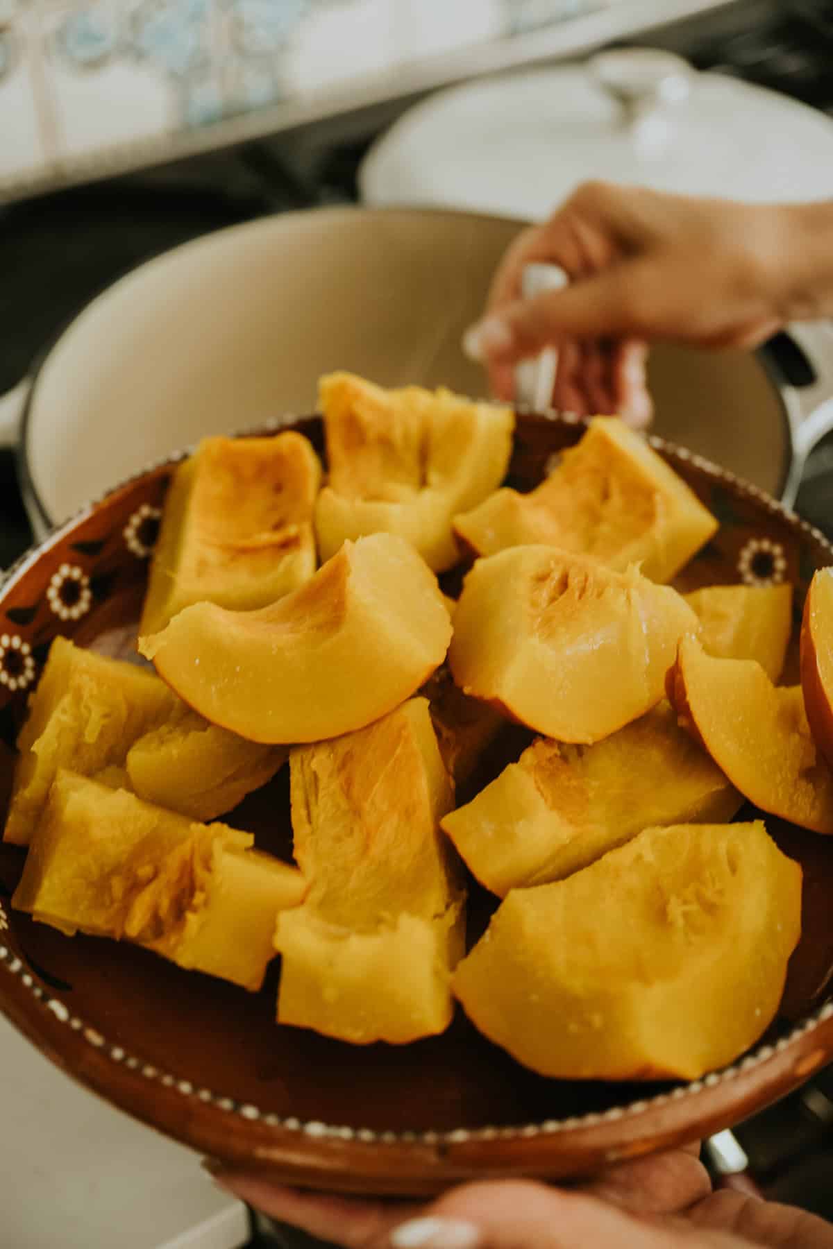 Cooked pumpkin pieces cooling in a clay bowl.