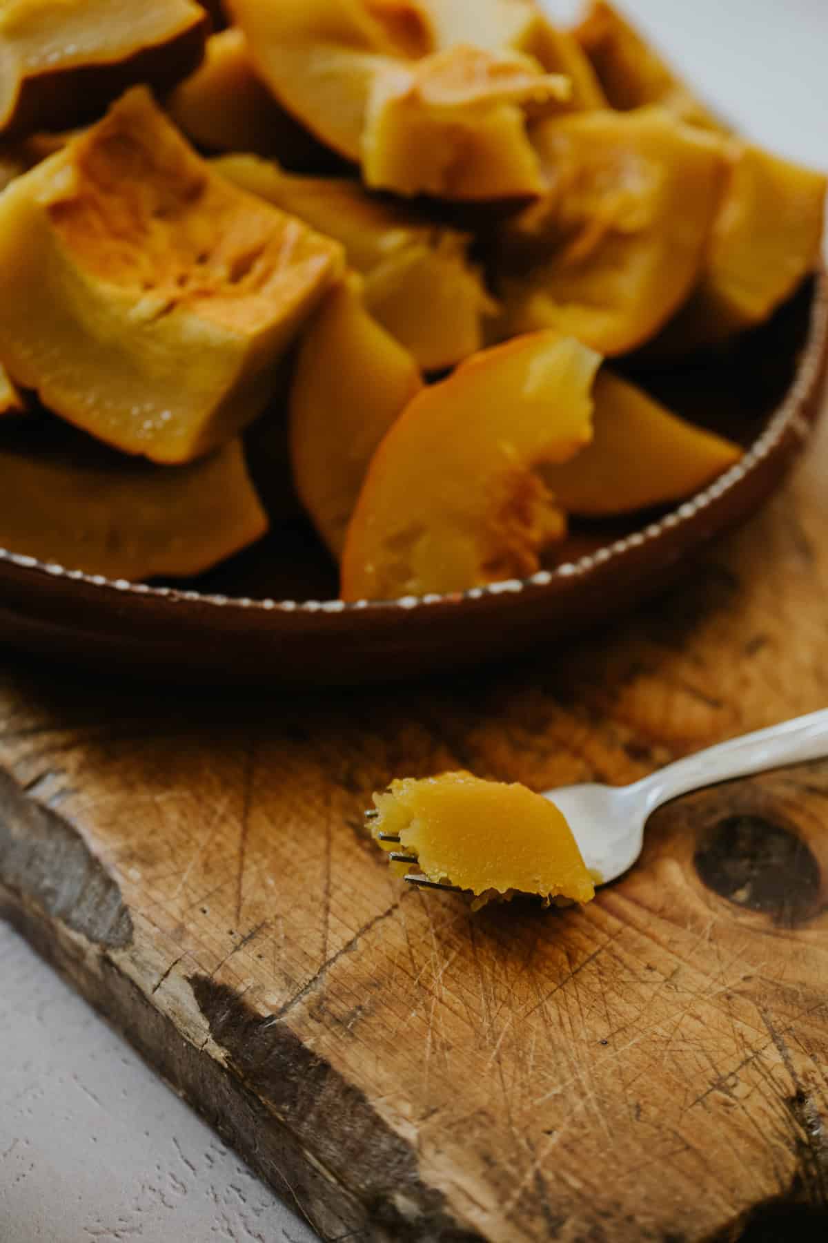 Cubes of steamed pumpkin arranged on a wooden board.