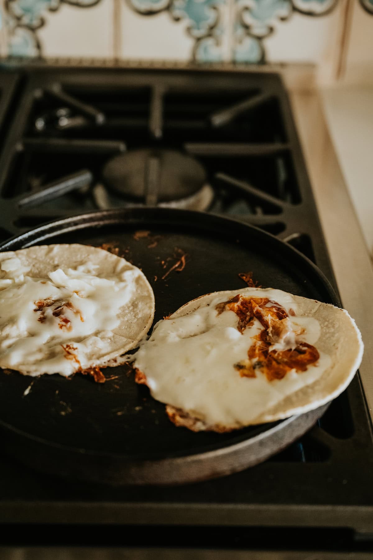 Corn tortillas pressed over melted Oaxaca cheese on a hot comal.