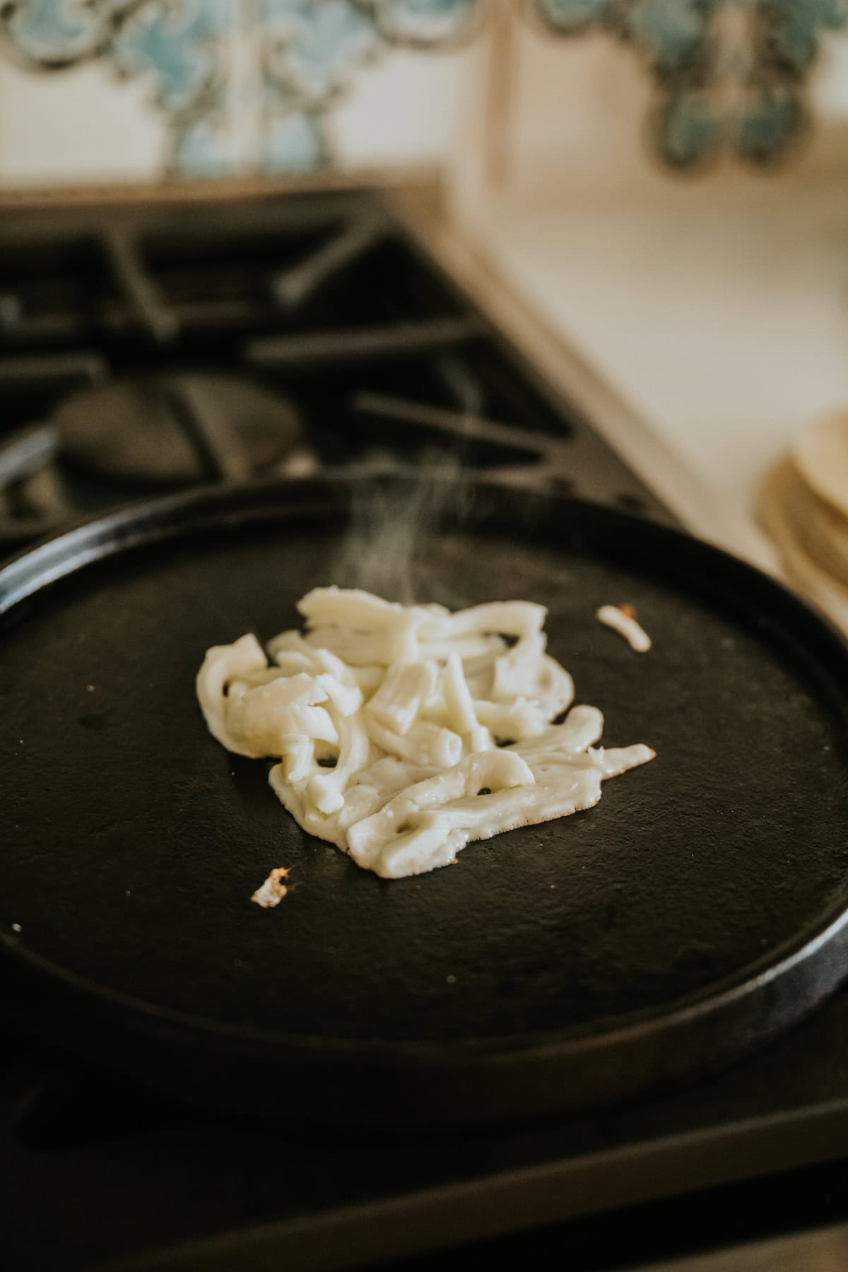 Oaxaca cheese melting on a comal until golden and bubbly.