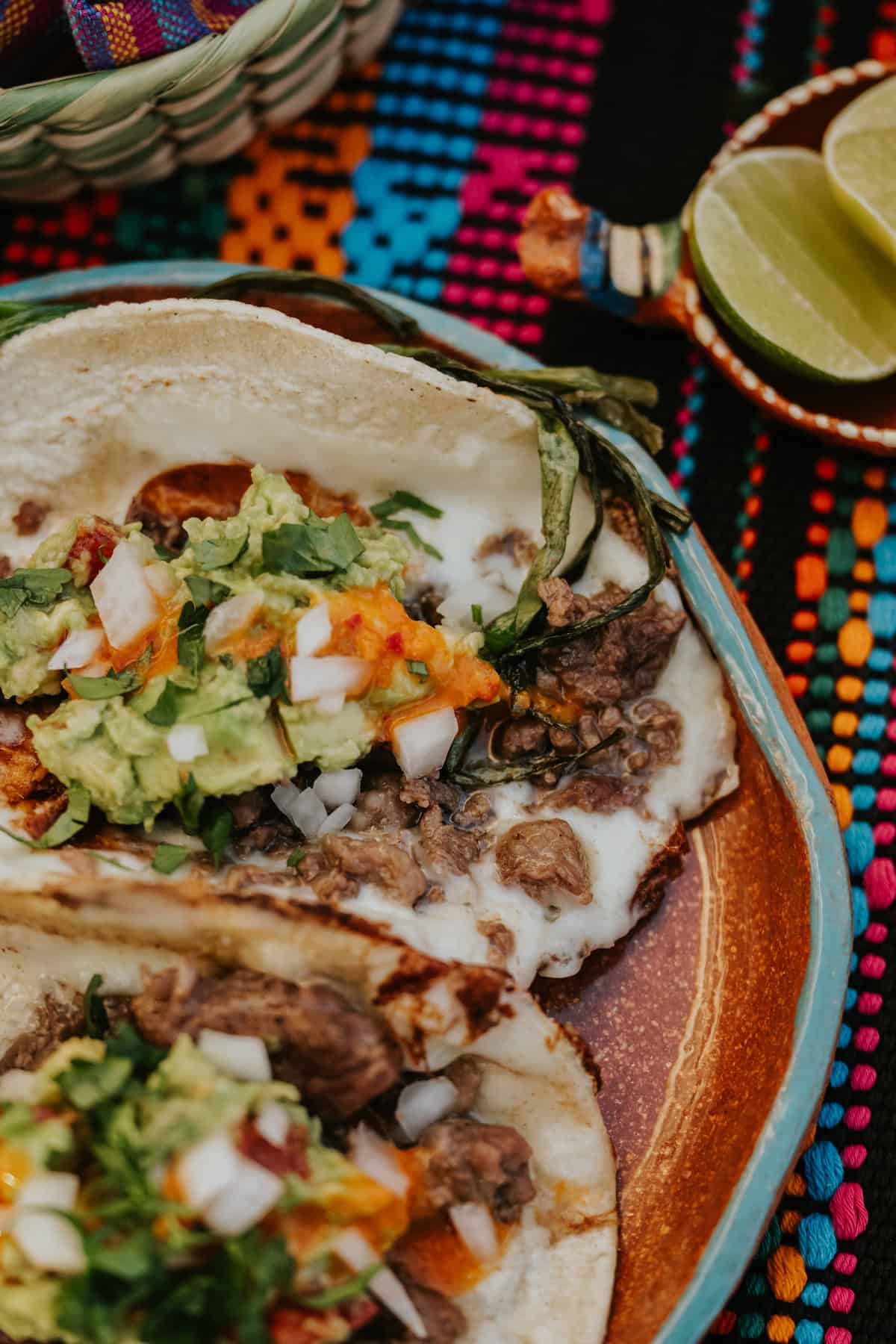 Close-up of steak tacos with crispy melted cheese, salsa, and cilantro on top.