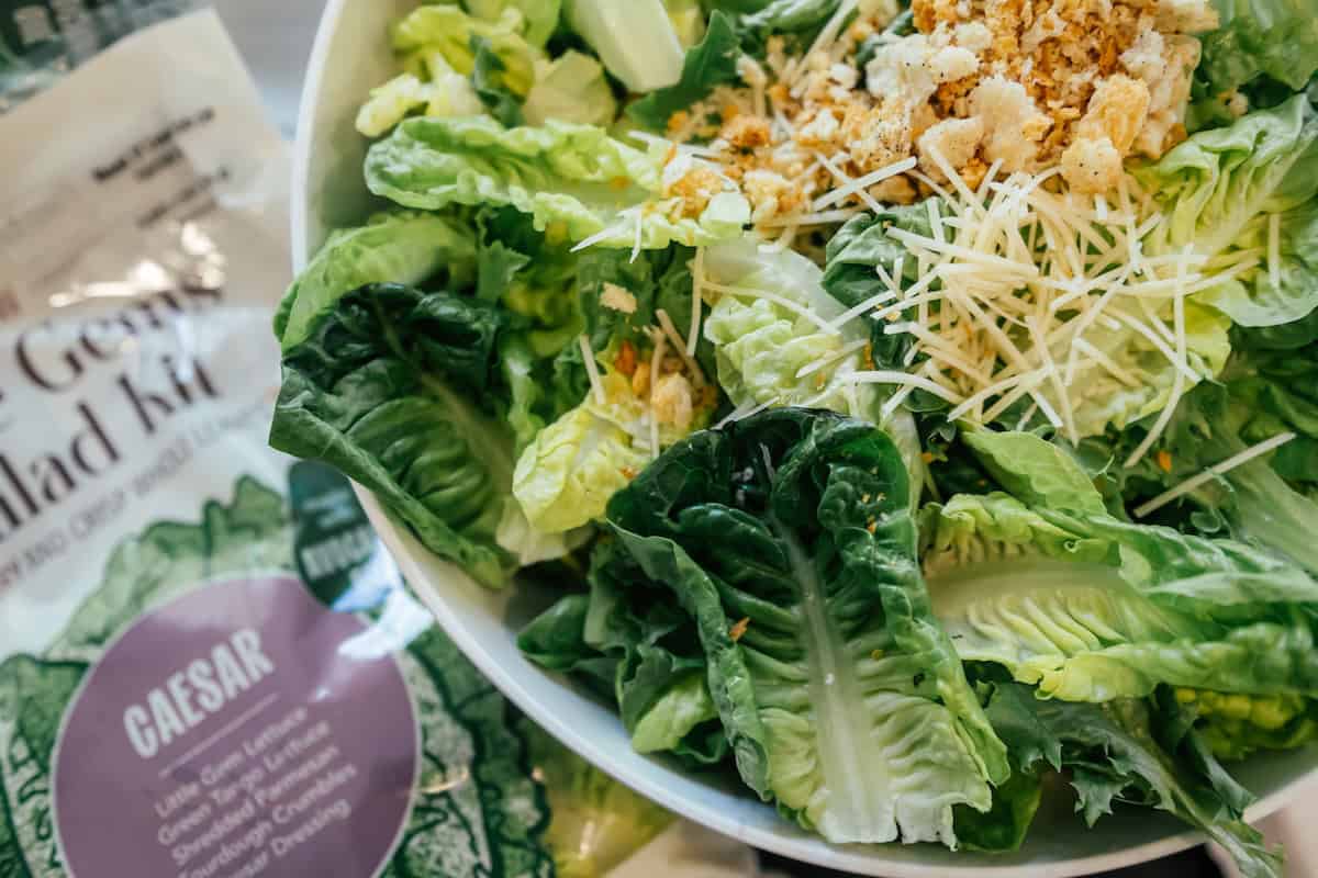 Little Gems Caesar salad from Church Brothers Farms with crisp lettuce, shredded cheese, and crunchy toppings served in a bowl alongside the salad kit packaging.