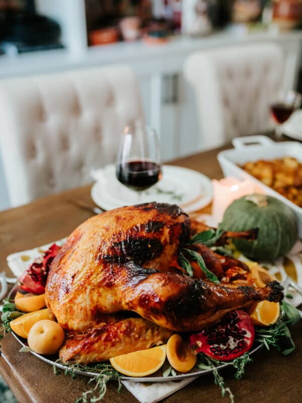 Pavo Enchilado Mexican roast turkey glazed with apricot butter and red chile sauce, garnished with oranges and fresh herbs on a Thanksgiving table.